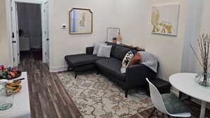 Una sala de estar moderna con un sofá modular, una mesa de comedor y una pequeña cocina.