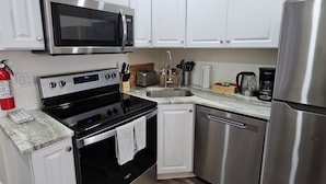 Cocina moderna con armarios blancos, electrodomésticos de acero inoxidable y encimera de granito.