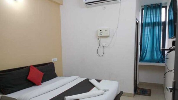 Habitación de hotel con cama, aire acondicionado de pared, teléfono y ventana con cortinas.
