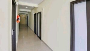 Un pasillo con puertas a ambos lados, un extintor a la izquierda y una lámpara en el techo.