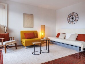 A modern living room with a yellow sofa, a white sofa, a round coffee table, a wooden chair, a floor lamp, and a wall clock. - Jolimont J4 by Interhome (Nendaz)