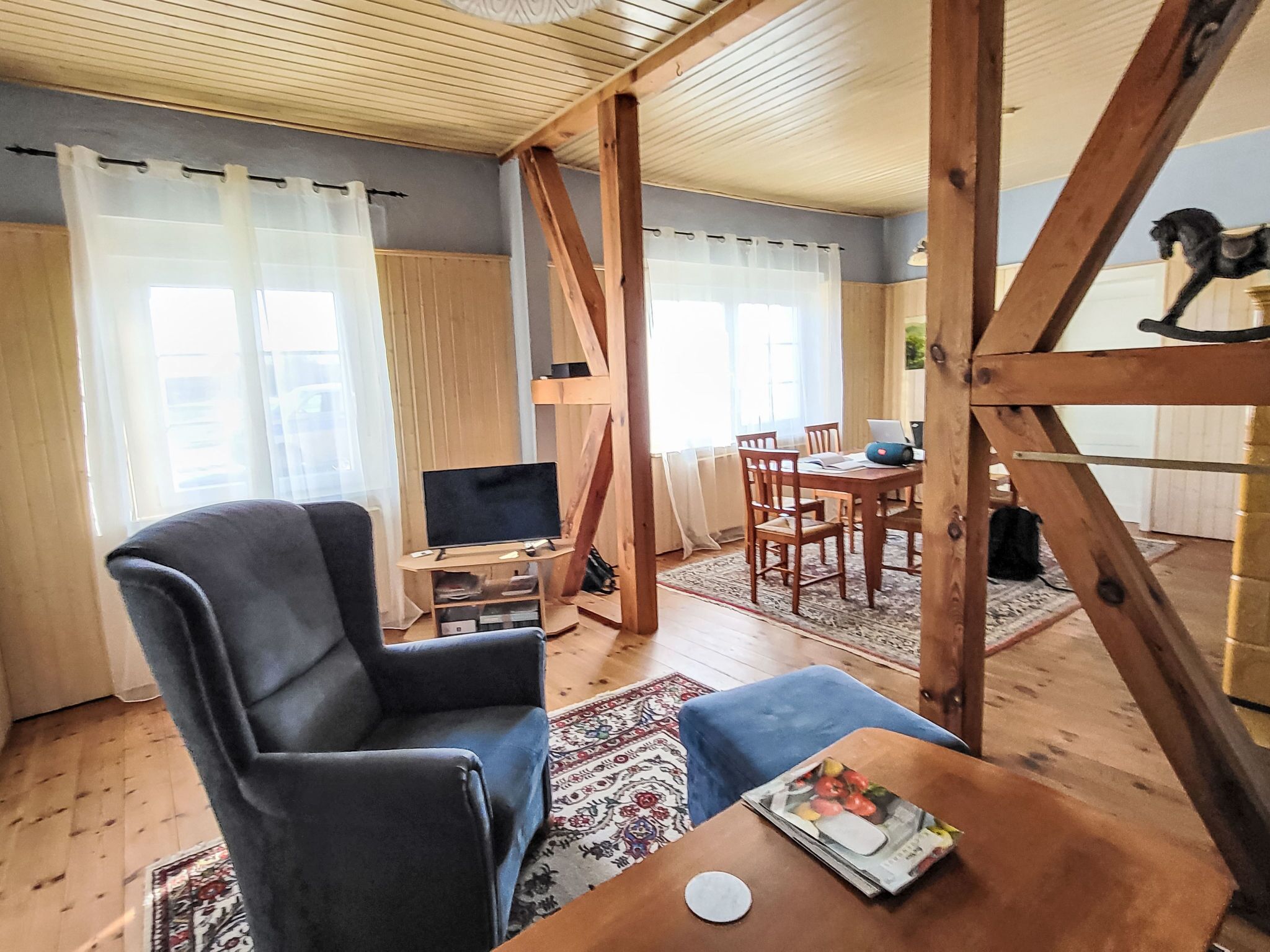 Una sala de estar con un sillón de cuero grande, una mesa de comedor de madera y un televisor sobre un mueble de madera.