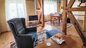 A living room with a large leather armchair, a wooden dining table, and a television on a wooden stand. - Mit großem Garten by Interhome (Hohenbucko)
