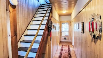 Ein Holzinnenraum mit Treppe, Flur und einer Tür mit Fenstern.
