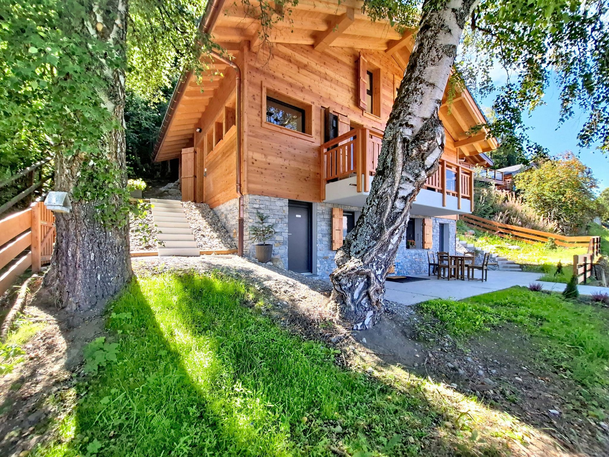 Une cabane en bois avec des fondations en pierre, un balcon et un escalier menant à l’entrée.