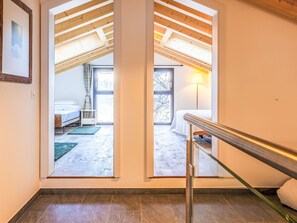 Ein modernes Interieur mit einer Treppe, einem Bett und Blick durch eine Glastür.