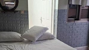 Una cama con ropa de cama blanca, una colcha estampada y una ventana con cortinas.
