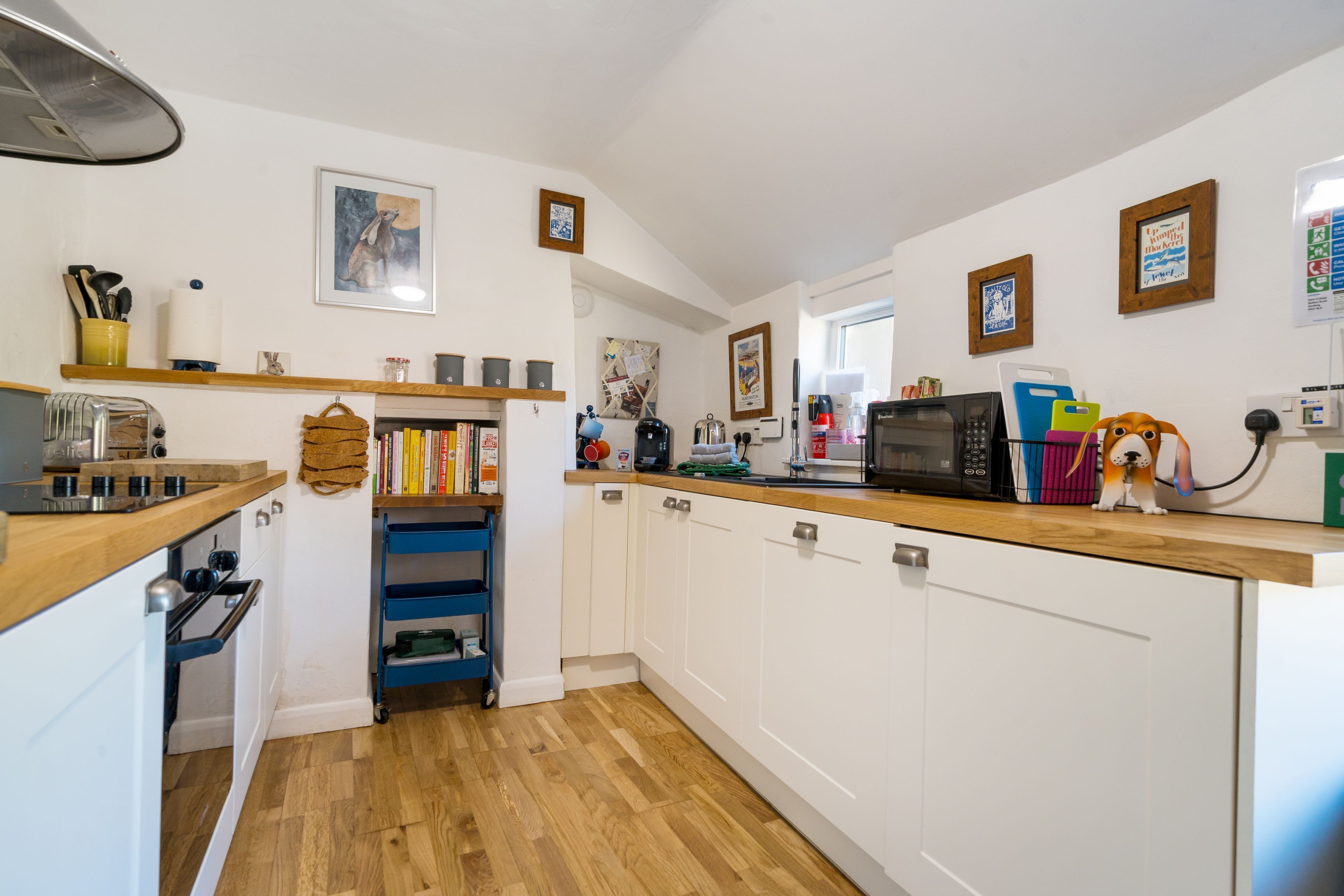 A compact kitchen with white cabinets, a wooden countertop, and a built-in oven.