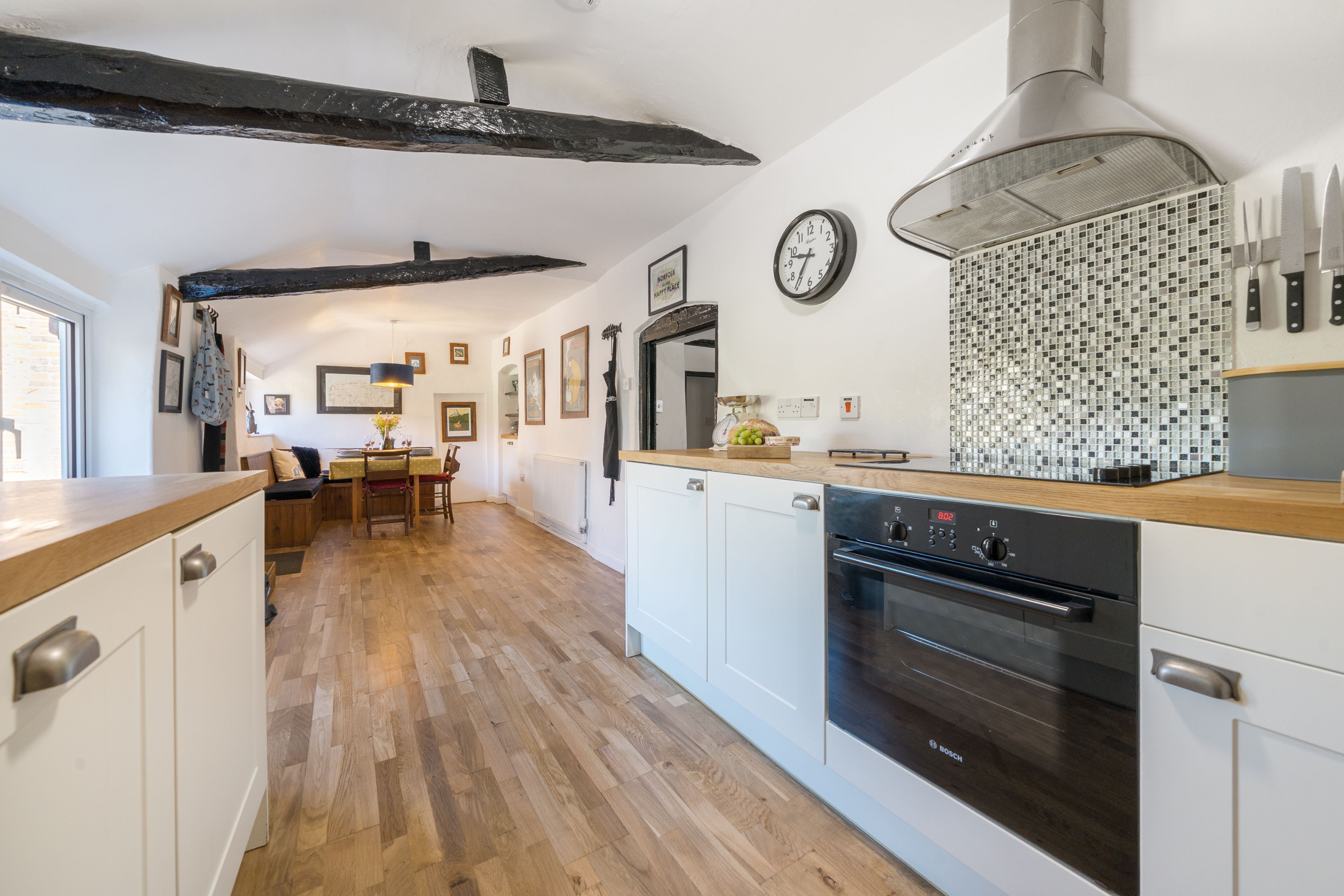 Une cuisine moderne avec des meubles blancs, un four Bosch et un plan de travail en bois.