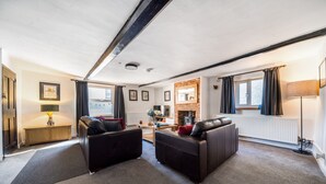 Una sala de estar moderna con dos sofás de cuero, una chimenea y un ventanal con cortinas.