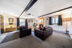 A modern living room with two leather sofas, a fireplace, and a large window with curtains. - Hare Cottage - sleeps 4 guests  in 2 bedrooms (Docking)