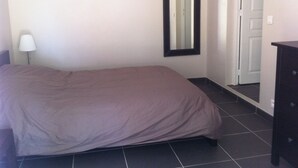 Ein Schlafzimmer mit einem Bett, einem Nachttisch, einer Lampe, einer Kommode und einer Tür.