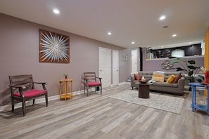 A living room with a sofa, two wooden chairs, a coffee table, and a rug.