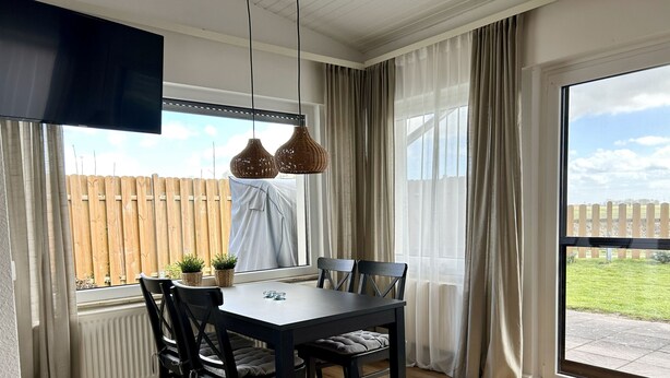 Un espace repas comprenant une table, des chaises et des luminaires suspendus.