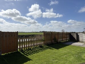 A wooden fence, a grassy area, and a clear sky with clouds.