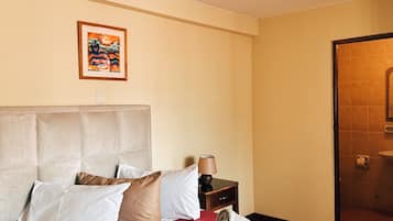 Une chambre d’hôtel avec un grand lit, une table de chevet, une lampe et un tableau au mur.