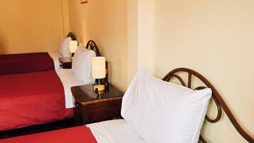 A hotel room with two beds, each with a red and white bedspread, a wooden nightstand with a lamp, and a framed picture on the wall.