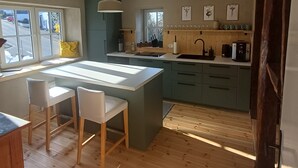 A modern kitchen with a central island, wooden flooring, and a view through large windows. - SOUTH1 - Peace and quiet between Moselle and Hunsrück (Grenderich)