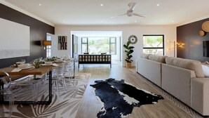 A modern living room with a sofa, a dining table set for a meal, and a large window providing natural light.
