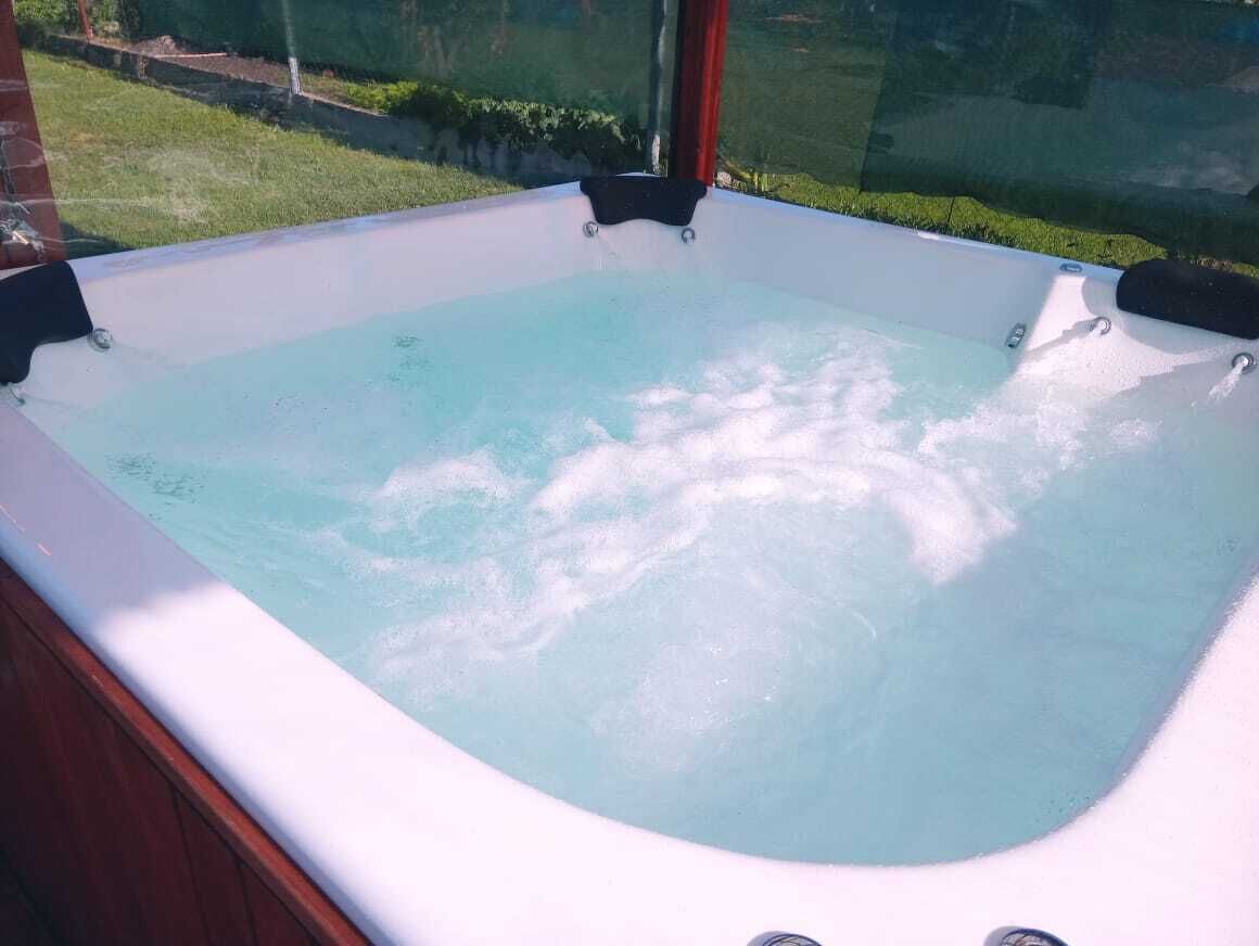 Un jacuzzi con vistas despejadas al jardín circundante y una pared de vidrio.