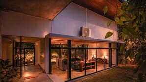 Una casa moderna con un porche acristalado, mobiliario exterior y una mesa central.