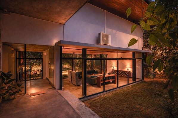 A modern house with a glass-enclosed patio area featuring outdoor furniture and a central table.