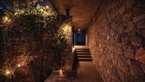 Un estrecho pasillo de paredes de piedra con una escalera que lleva a una puerta.