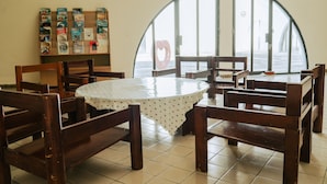 A restaurant with a round table, wooden chairs, a bulletin board with various items, and a large arched window with a heart-shaped decoration. - tienhsiang youth activity center (Xiulin)