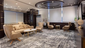 Un'elegante area lounge con divano, poltrone, tavolino e tappeto decorato.