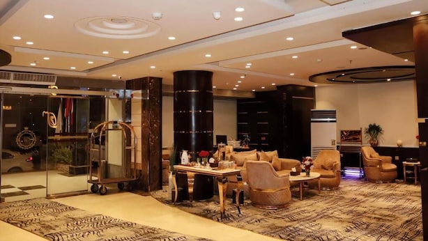 Spaziosa hall con ampia area salotto, reception e soffitto alto con illuminazione a incasso.