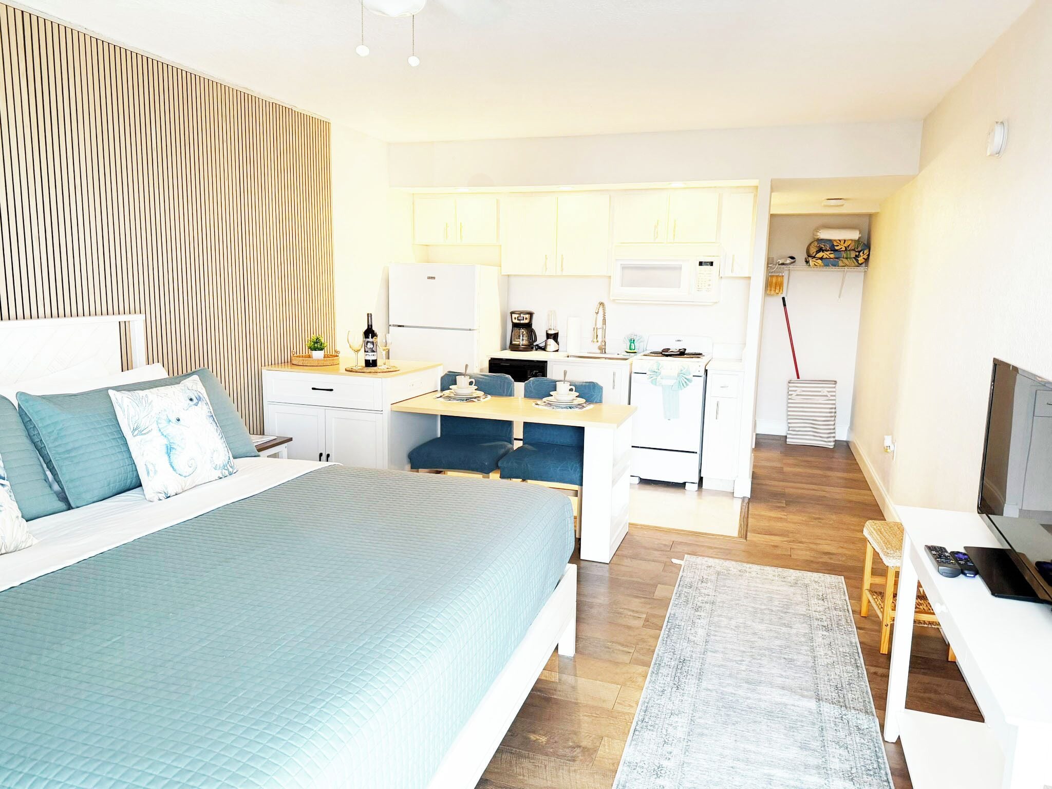 Una habitación de hotel moderna con cama, escritorio, kitchenette y televisor.