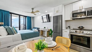 Eine moderne Küche mit Flachbildfernseher, Edelstahlgeräten und einer Essecke mit Holztisch und -stühlen.