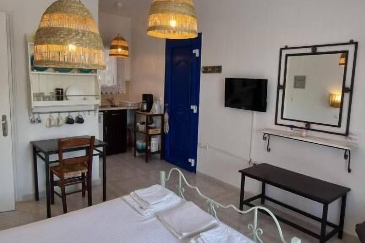 Une chambre d’hôtel avec un lit, un bureau, une chaise, une télévision et une porte de salle de bain.