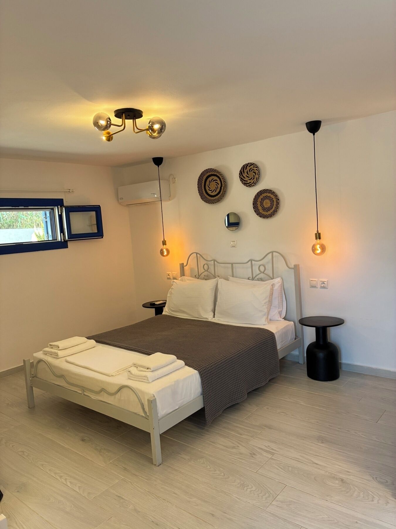 A bedroom with a bed, bedside tables, wall-mounted decor, and a window.