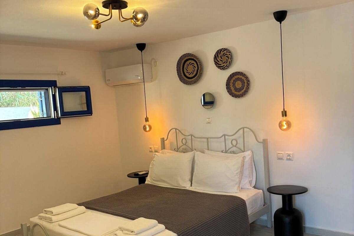 Une chambre à coucher comprenant un lit, des tables de chevet, des éléments de décoration fixés au mur et une fenêtre.