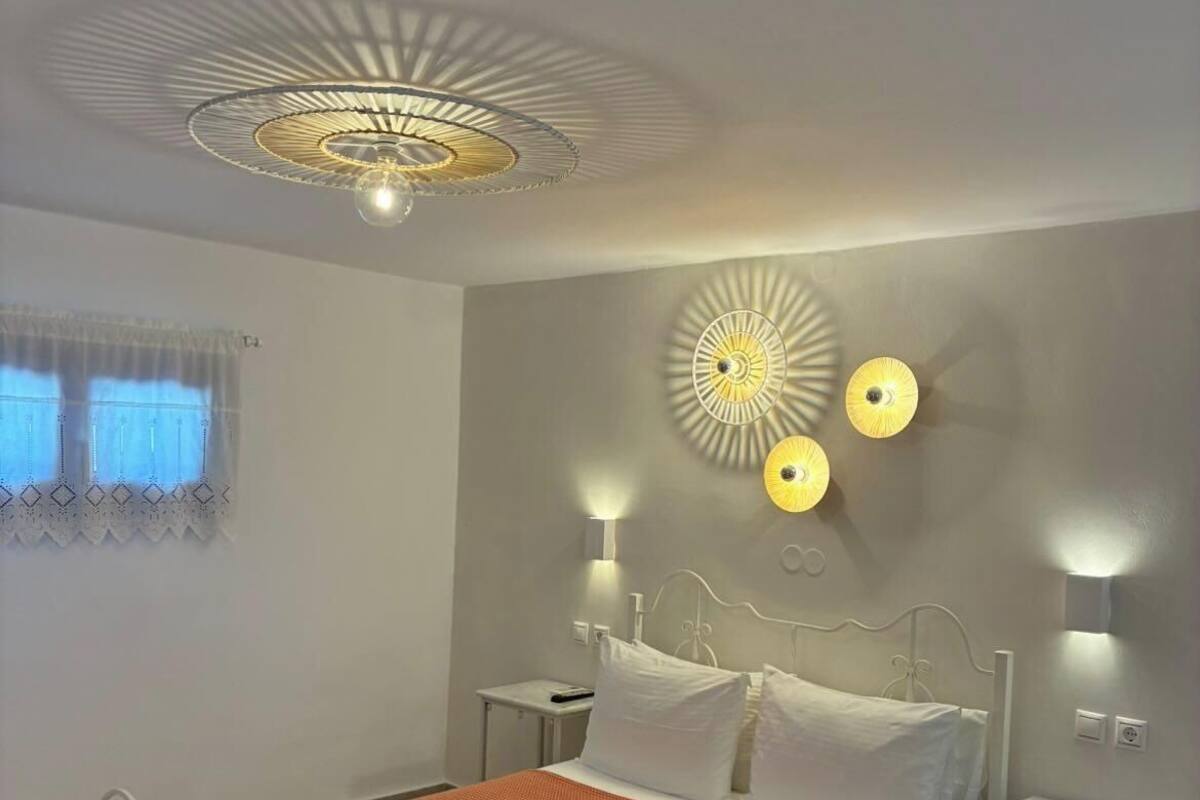 Une chambre à coucher moderne, comprenant un lit, des tables de chevet, un luminaire au plafond et des lampes fixées au mur.