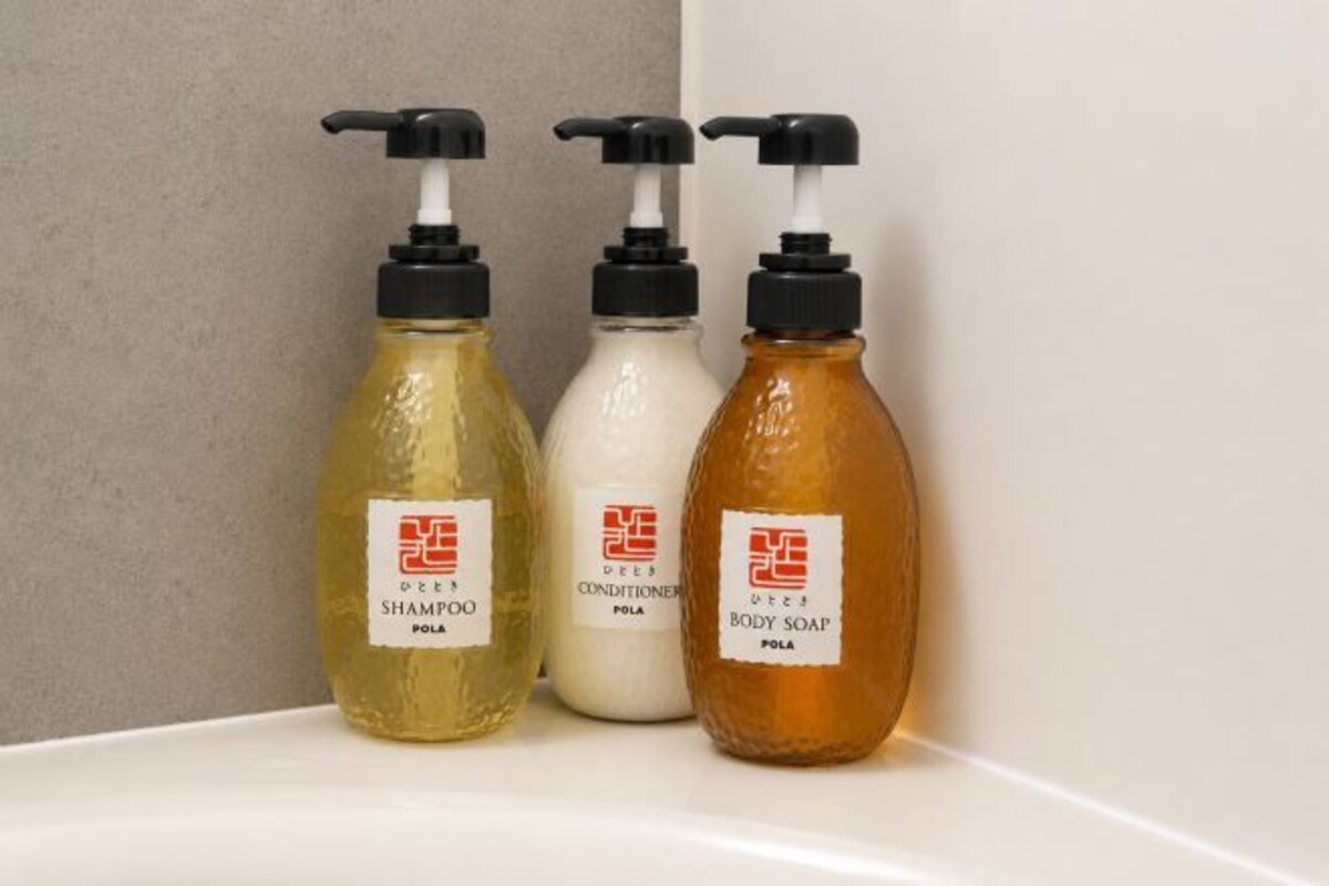 Three bottles of shampoo, conditioner, and body soap on a white surface.