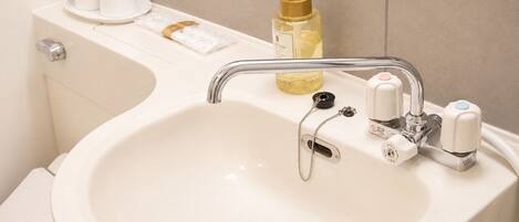 A bathroom sink with a chrome faucet, a soap dispenser, and a toilet paper holder.