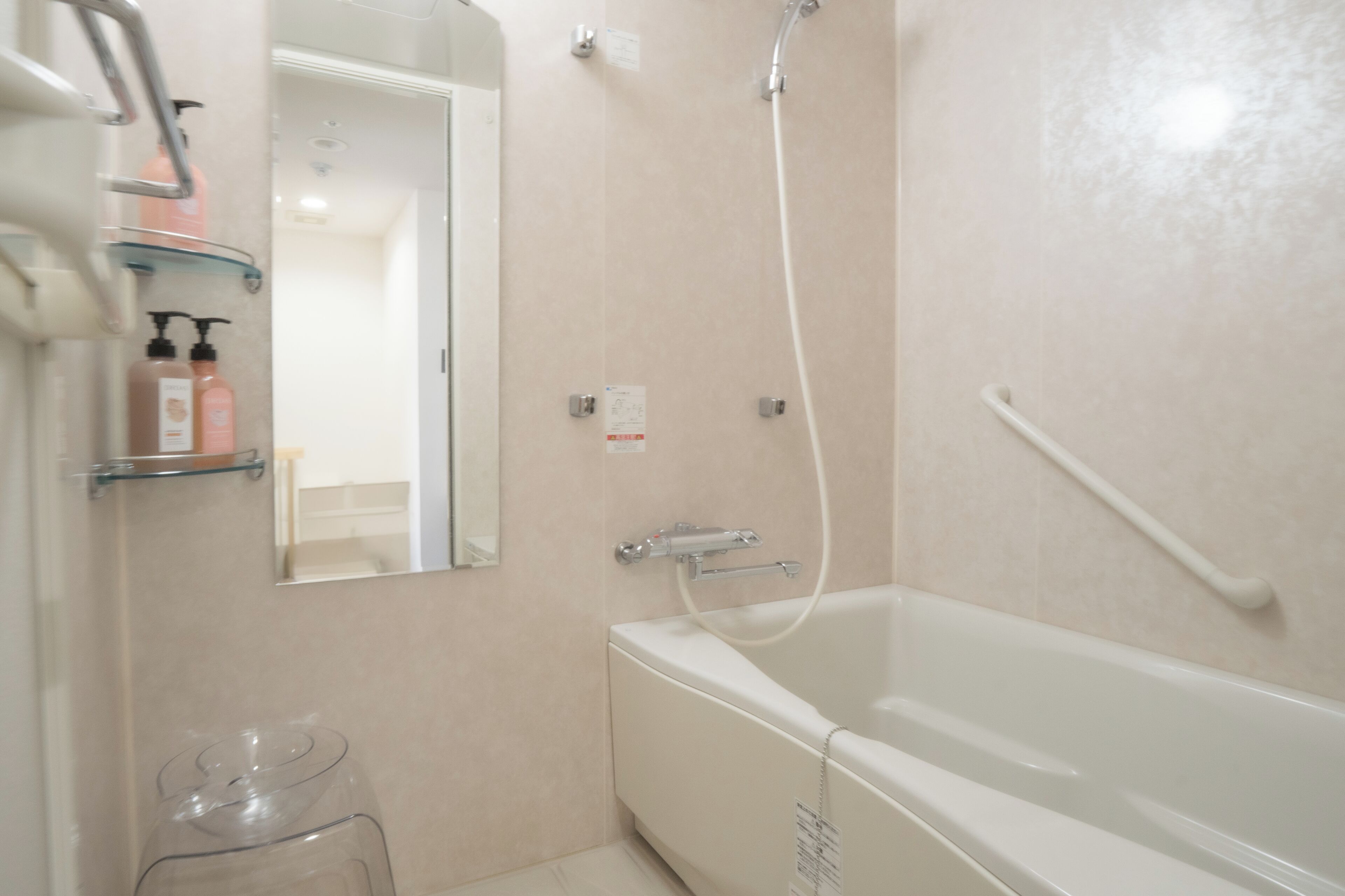 A modern bathroom with a bathtub, a shower, and a glass jar on the floor.