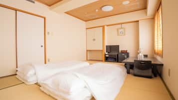 Habitación de hotel con dos camas, un escritorio, una silla, un televisor y una ventana con persianas.