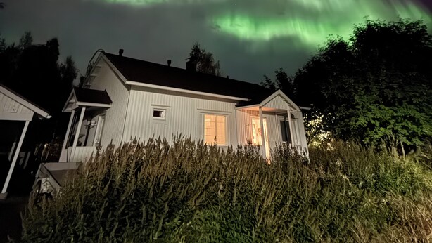 A house with a visible front porch and a view of the Northern Lights. - Cozy home with sauna and kota (Rovaniemi)