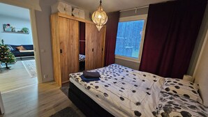 A bedroom with a bed, wooden wardrobe, and a window with curtains. - Cozy home with sauna and kota (Rovaniemi)