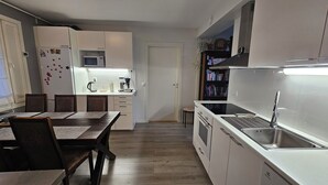 A compact kitchen with a dining area, white cabinets, a microwave, a coffee maker, and a sink. - Cozy home with sauna and kota (Rovaniemi)