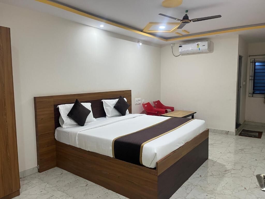 Une chambre à coucher bien rangée, avec un lit en bois, une petite table et une chaise rouge.