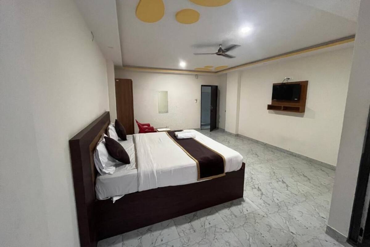 Ein Hotelzimmer mit einem großen Bett, einem Deckenventilator, einem an der Wand montierten Flachbildfernseher und einem Marmorboden.