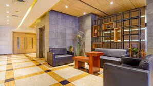 A modern lobby with a checkered floor, seating area, and a wooden ceiling. - Townhouse Dindigul Rock Fort Formerly Ramora Grand (Thindukkal)