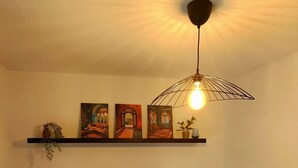 Ein Schlafzimmer mit einem Bett, zwei Kissen, einem Nachttisch, einer Lampe und einem Regal mit drei Bildern.
