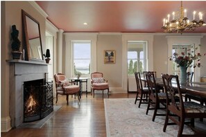 A room with a fireplace, dining table, chairs, and a chandelier. - Private Beach with Views: Stonehouse Estate, Near Wine Trail and Spa (Aurora)