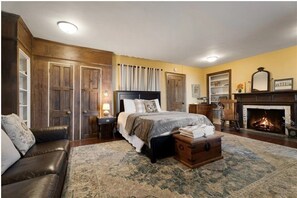 A bedroom with a large bed, a fireplace, a wooden dresser, and a leather sofa. - Private Beach with Views: Stonehouse Estate, Near Wine Trail and Spa (Aurora)