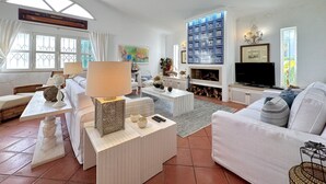 Un salon avec un canapé, une table basse, un téléviseur et une cheminée.
